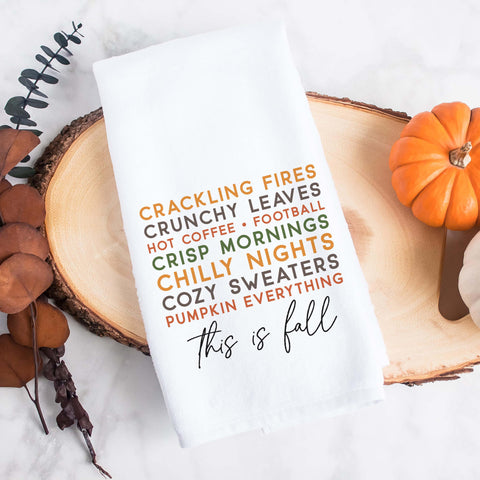 A fall tea towel printed with a list of fall favorites: crackling fires, crunchy leaves, hot coffee, crisp mornings, chilly nights, football, cozy sweaters, pumpkin everything, this is fall.  This can be used as a hand towel, kitchen towel, decorative towel, bathrooom towel, and more.